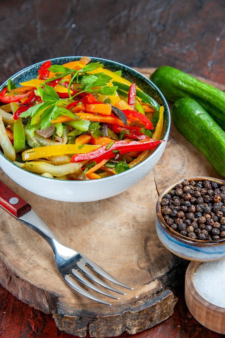 bottom-view-vegetable-salad-bowl-cucumbers-fork-black-pepper-rustic-board-salt-dark-red-table_140725-102869.jpg