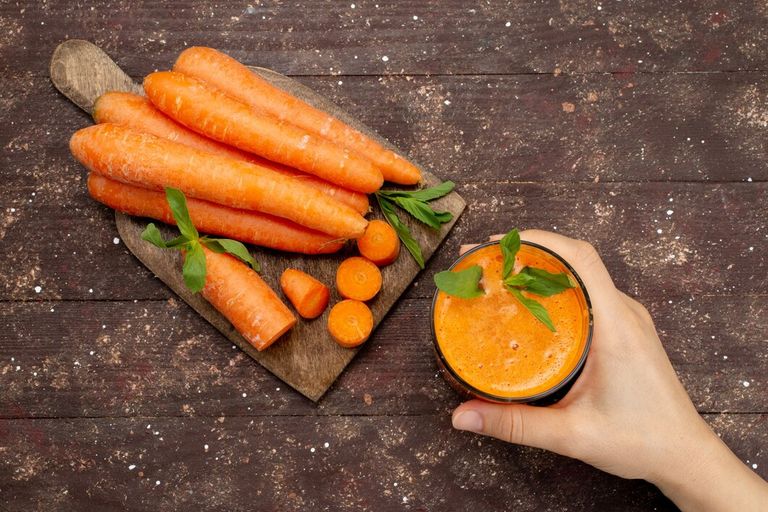 top-view-fresh-carrot-juice-inside-long-glass-with-leaf-along-with-fresh-carrots-brown_140725-18973.jpg