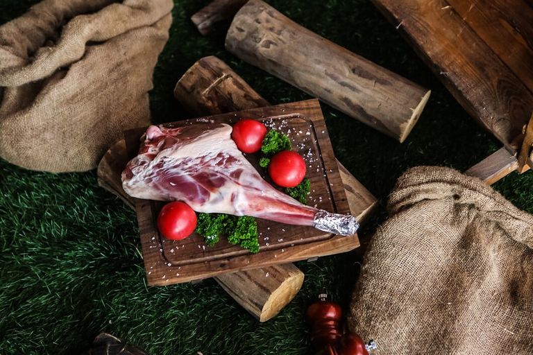 raw-lamb-leg-wooden-board-salt-tomato-greens-woods-top-view_141793-12471.jpg