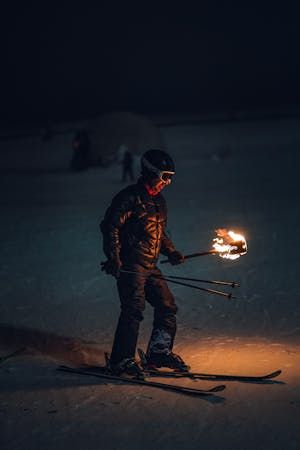 free-photo-of-male-skier-standing-outdoors-at-night-with-a-burning-torch-in-hand.jpeg