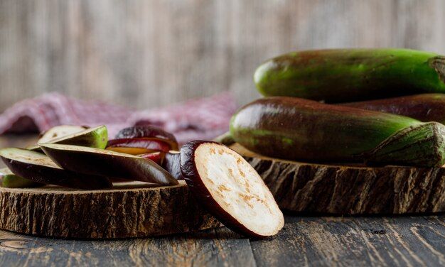 eggplants-with-slices-wood-pieces-side-view-wooden-kitchen-towel_176474-7277.jpg