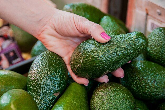 cropped-image-customer-choosing-avocados-supermarket-close-up-woman-hand-holding-avocado-market-sale-shopping-food-consumerism-people-concept_1391-641.jpg