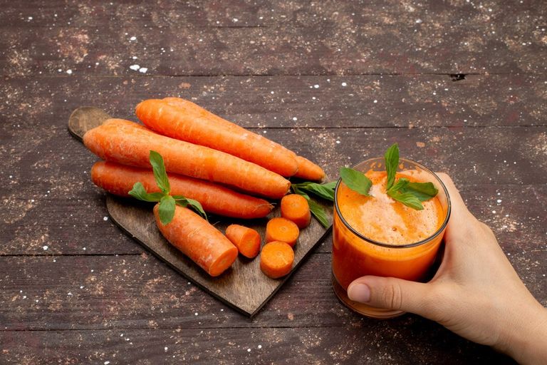 front-view-fresh-carrot-juice-inside-long-glass-with-leaf-along-with-fresh-carrots-brown-desk_140725-23106.jpg