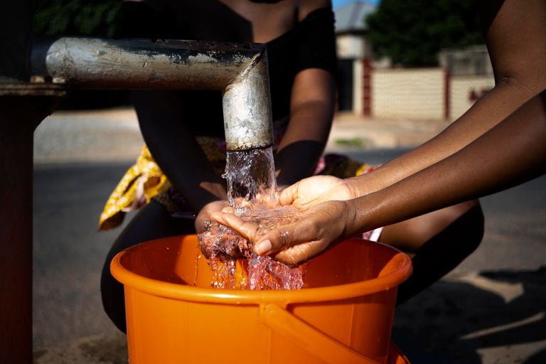 african-woman-pouring-water-recipient-outdoors.jpg