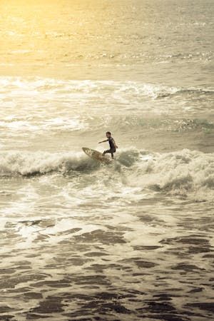 free-photo-of-surfer-riding-waves-at-sunset-beach.jpeg