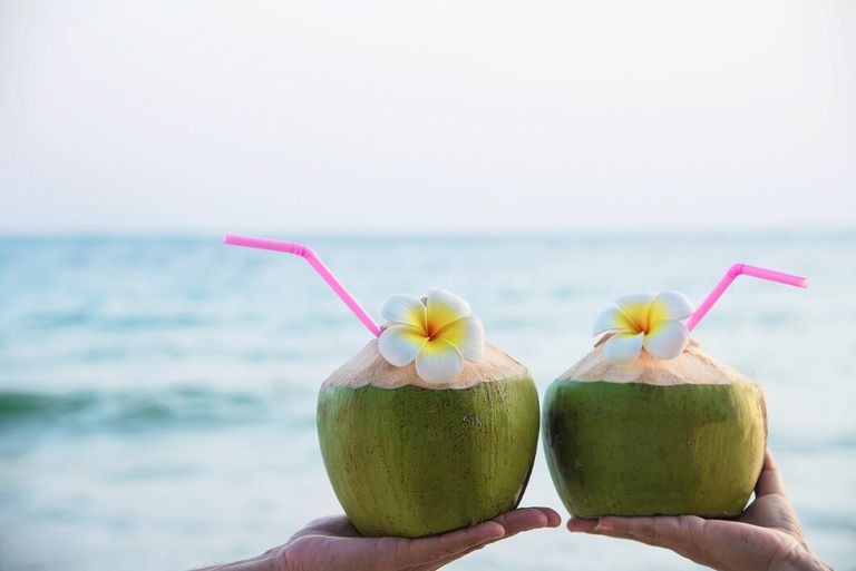 fresh-coconut-couple-hands-with-plumeria-decorated-beach-with-sea-wave-honeymoon-couple-tourist-with-fresh-fruit-sea-sand-sun-vacation-concept_1150-13509.jpg