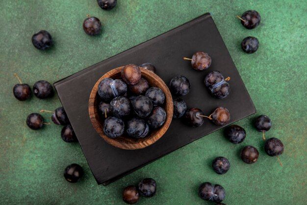 top-view-small-sour-blue-black-fruit-sloes-wooden-bowl-with-sloes-isolated-green-background_141793-20714.jpg