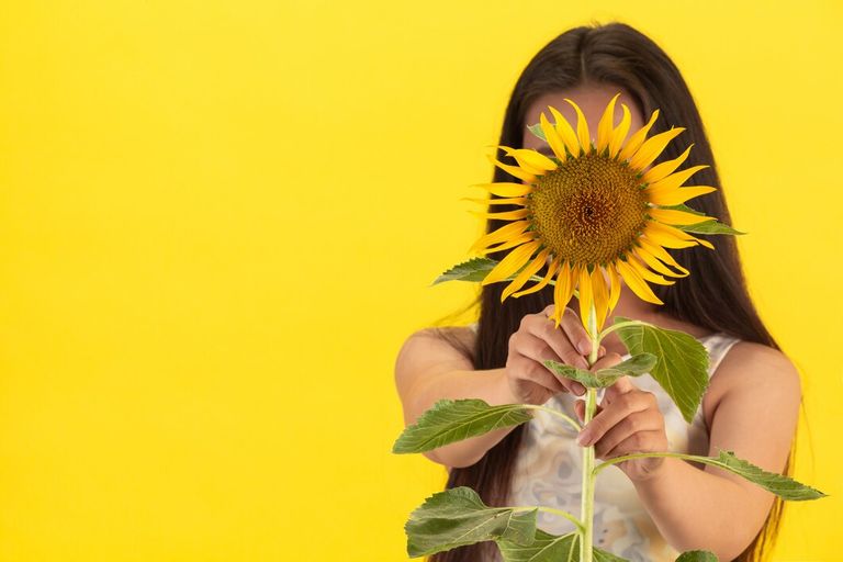 beautiful-woman-holding-sunflower-yellow-background_1150-23036.jpg