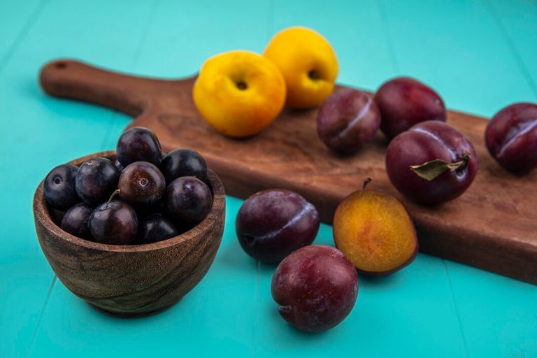 side-view-fruits-as-bowl-grape-berries-with-nectacots-pluots-cutting-board-blue-background_141793-27391.jpg