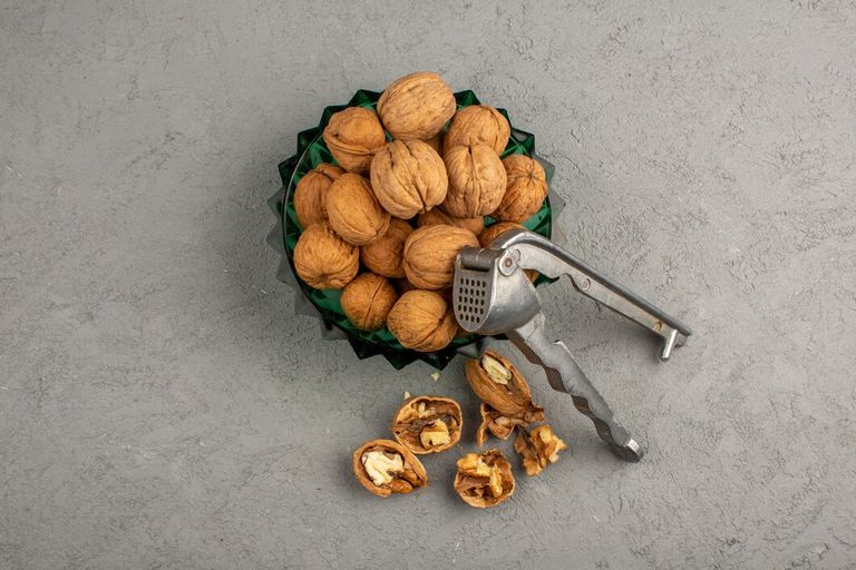 walnuts-top-view-brown-whole-inside-green-plate-grey-floor_179666-337.jpg