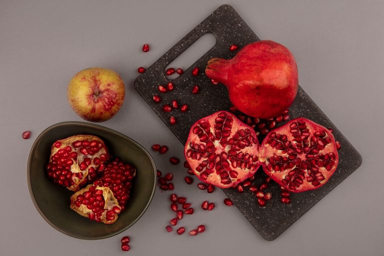 top-view-fresh-halved-whole-pomegranates-black-kitchen-board-with-open-pomegranates-bowl_141793-88690.jpg