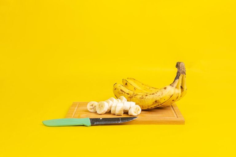 closeup-ripe-bananas-cutting-board-with-knife-it-isolated-yellow-background_181624-57153.jpg