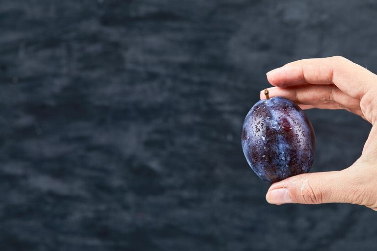 hand-holding-fresh-plum-dark-background_114579-20833.jpg