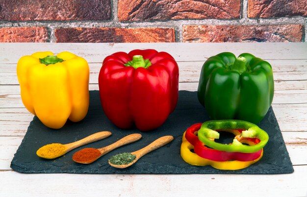 whole-sliced-red-green-yellow-peppers-three-wooden-spoons-with-spices-black-stone-board_251317-42.jpg