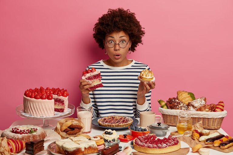 emotional-surprised-dark-skinned-woman-eats-cake-cupcake-surrounded-by-tasty-homemade-desserts-has-unhealthy-nutrition-cannot-believe-something_273609-39242.jpg
