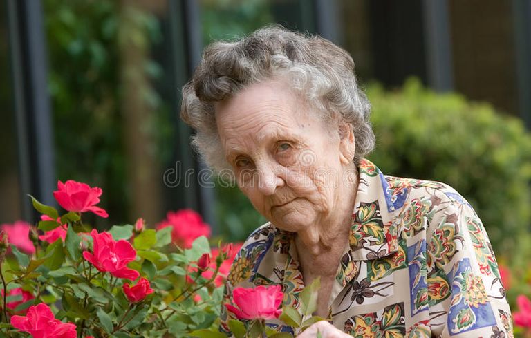 elderly-woman-smelling-flowers-19147234.jpg