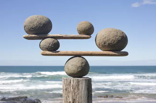 rocks-balancing-on-driftwood--sea-in-background-153081592-591bbc3f5f9b58f4c0b7bb16.webp